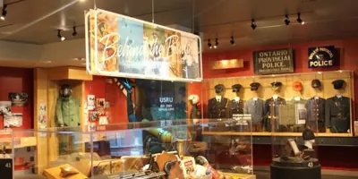 Interior view of a museum exhibit in Orillia featuring historic uniforms, artifacts, and interpretive displays about the Ontario Provincial Police in a brightly lit gallery space.