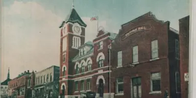 A vintage photograph of a bricked building with a clock tower in Downtown Orillia