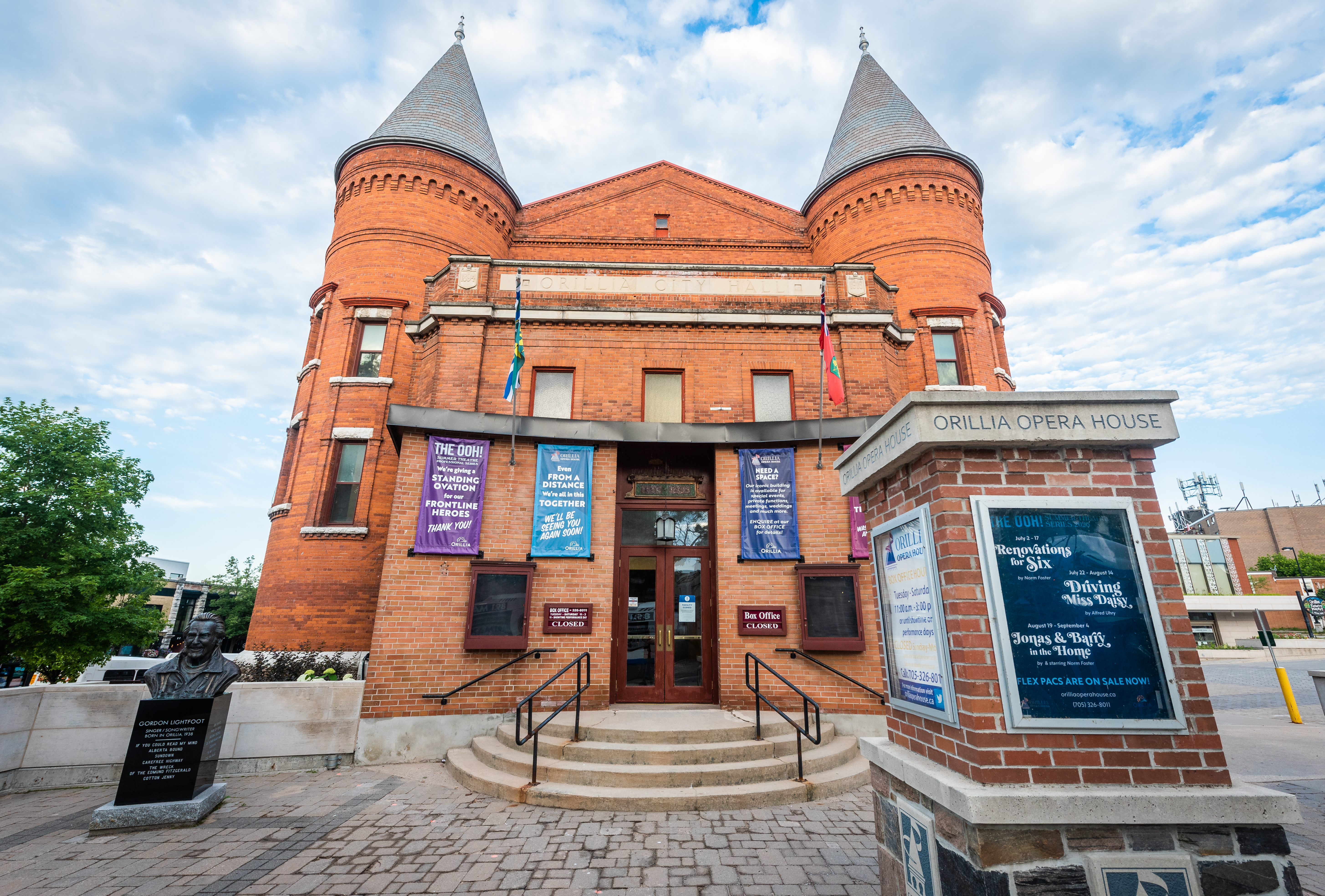 Front view of the Orillia Opera House, a historic red brick building with twin turrets, theatre banners, and a marquee in downtown Orillia.