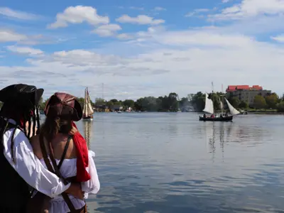 A couple in pirate costumes embrace while watching an in-water boat show during the Pirate Party