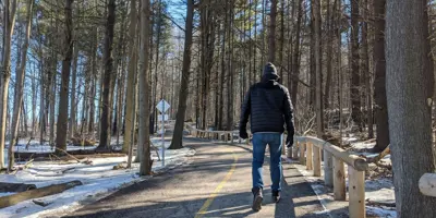 A man walks along a paved winter trail